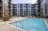 Modern apartment complex with sleek exterior design and inviting swimming pool surrounded by stylish lounge chairs.