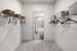 Spacious walk-in closet with organized shelving and hangers leading to a modern bathroom, perfect for stylish storage solutions.