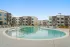 Resort-style swimming pool at an apartment community with lounge chairs, umbrellas, and landscaped surroundings