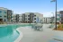Resort-style swimming pool at an apartment community with lounge chairs, umbrellas, and landscaped surroundings