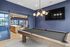 Modern apartment game room with a sleek pool table, vibrant blue walls, and an inviting sitting area in the background.