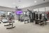 Modern fitness center with state-of-the-art exercise equipment, large windows for natural light, and a vibrant wall-mounted TV, ideal for an energizing workout.