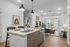 Modern open-concept kitchen and living room with chic decor, featuring stylish pendant lights and natural light through large windows.