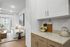 Contemporary living area with elegant white cabinetry and cozy sofa, featuring a stylish lampshade and vibrant potted plant, offering a serene and inviting ambiance.