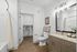 Modern bathroom with stylish wood flooring, elegant vanity with granite countertop, spacious walk-in closet, and contemporary wall art.