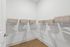 Spacious walk-in closet featuring elegant white shelving, organized hangers, and chic wicker storage baskets.