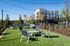 Charming outdoor seating area with modern patio furniture, overlooking a stylish apartment complex, highlighted by string lights and landscaped greenery.