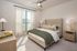 Inviting bedroom with elegant beige decor, plush bedding, and natural light streaming through large windows.