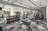 Modern fitness center with diverse equipment, large windows overlooking a pool, and stylish geometric flooring.