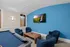 Cozy entertainment room featuring a blue pool table, modern armchairs, and a wall-mounted TV on a vibrant blue accent wall.