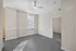 Bright and modern room with large window, ceiling fan, and stylish gray flooring, offering plenty of natural light.