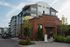 Modern apartment complex with stylish brick leasing office and attractive greenery, perfect for young professionals.