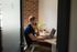 Modern office space with a stylish person working on a laptop, featuring exposed brick walls and natural light.