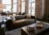Chic loft-style lounge with exposed brick walls, large windows, and stylish leather sofa. Features a pool table and modern d&eacute;cor for a sophisticated living experience.