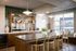 Modern kitchen with stylish wood cabinetry, elegant green tiled backsplash, and a spacious black countertop island with gold bar stools.