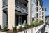 Modern apartment complex with a dedicated fitness center entrance, surrounded by lush landscaping and balconies under a clear blue sky.