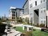 Modern apartment complex exterior showcasing stylish grey siding, large windows, and inviting outdoor seating area with beautiful landscaping.