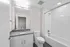 Elegant modern bathroom showcasing sleek granite countertop, large mirror, and pristine tile bathtub.