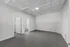 Spacious and modern room with sleek gray flooring, bright white walls, and a textured ceiling, featuring a bathroom and a closet for added convenience.