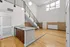 Modern apartment with high ceilings, sleek wooden flooring, stylish staircase, and elegant granite kitchen countertop.