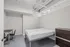Modern minimalist bedroom with a sleek metal bed, stylish dresser, and functional desk chair set against crisp white walls and a contemporary ceiling design.