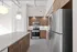 Modern kitchen with stainless steel appliances, sleek countertops, and stylish wooden cabinetry, illuminated by chic pendant lighting.