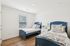 Bright and cozy bedroom featuring twin beds with elegant blue frames, stylish bedding, and a contemporary white nightstand.