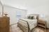 Bright and cozy bedroom featuring a plush bed with decorative pillows, a stylish wooden dresser, and elegant side tables with modern lamps.