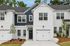 Charming townhouse exterior with a modern white brick finish and inviting front entryway, surrounded by lush greenery.