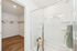 Inviting modern bathroom with a spacious walk-in closet, featuring elegant glass shower and contemporary wood flooring.