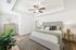 Inviting bedroom with plush king-sized bed, elegant ceiling fan, cozy lighting, and vibrant greenery, offering a serene retreat.