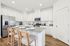 Modern kitchen with sleek granite countertops, stainless steel appliances, and stylish wooden bar stools under bright recessed lighting.