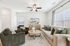 Elegant living room with a cozy beige sofa, chic armchairs, and a stylish round coffee table with decorative accents. Bright natural light streams through large windows, enhancing the contemporary decor and luxurious atmosphere.