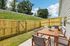 Charming fenced backyard with cozy patio setting featuring wooden dining table and chairs, perfect for outdoor relaxation and entertaining.