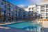 Modern apartment complex featuring a large swimming pool and sun loungers, perfect for relaxation and leisure.