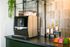 Chic modern coffee station with a sleek machine, flavor syrups, and a variety of gourmet teas.