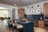 Elegant modern kitchen with sleek black countertops, wood cabinetry, and comfortable bar seating. Open layout extends into a bright, inviting living area, ideal for entertaining.