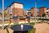 Charming outdoor patio area with modern grills, surrounded by stylish brick apartment buildings under a clear blue sky.