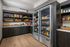 Modern pantry with sleek wooden cabinets, stocked shelves of snacks, and a well-lit beverage fridge.