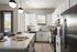 Modern kitchen with sleek white cabinetry, a spacious island with elegant pendant lighting, and stainless steel appliances.