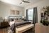 Modern bedroom with chic decor featuring a cozy bed, elegant lamps, and stylish artwork, bathed in natural light.