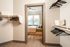 Inviting bedroom with ample natural light, seen through a modern walk-in closet with sleek hangers and contemporary shelving.