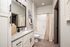 Modern bathroom with elegant marble countertop, large mirror, and a tidy bathtub, showcasing sleek black and white accents for a stylish look.