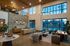 Elegant modern lobby with high ceilings, large windows, and chic furnishings, featuring a stylish stone accent wall and luxurious seating area.
