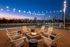 Inviting outdoor patio at dusk featuring cozy fire pit surrounded by Adirondack chairs, string lights above create a warm ambiance, ideal for evening relaxation.