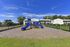 Inviting apartment complex with a vibrant blue playground, set against a backdrop of clear skies and lush greenery.