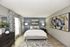 Modern bedroom with elegant decor, featuring a plush bed, chic artwork, and soothing neutral tones.