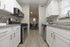 Modern kitchen with granite countertops, sleek stainless steel appliances, and elegant white cabinetry, leading to a cozy dining area with plush blue chairs.