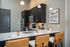Modern kitchen with sleek dark cabinetry, stainless steel appliances, and a chic breakfast bar with leather seating, perfect for stylish living.