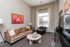 Elegant living room with a plush tan sofa, modern art, and bright natural light creating a warm, inviting atmosphere.